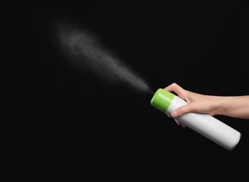 Woman spraying air freshener on black background, closeup