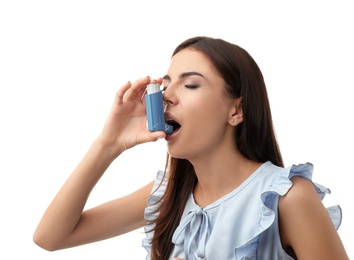 Young woman using asthma inhaler on white background