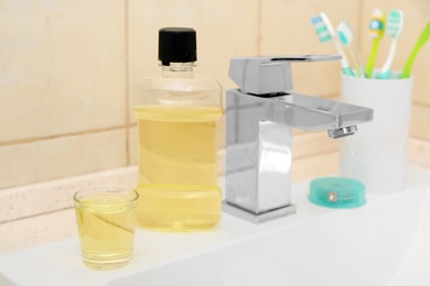 Mouthwash and holder with toothbrushes on sink in bathroom. Teeth and oral care