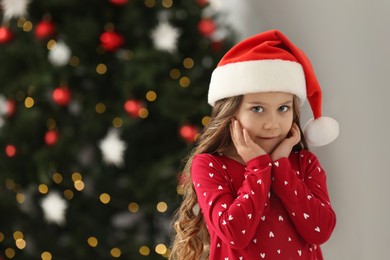 Photo of Portrait of cute girl wearing Santa hat at home, space for text. Christmas atmosphere