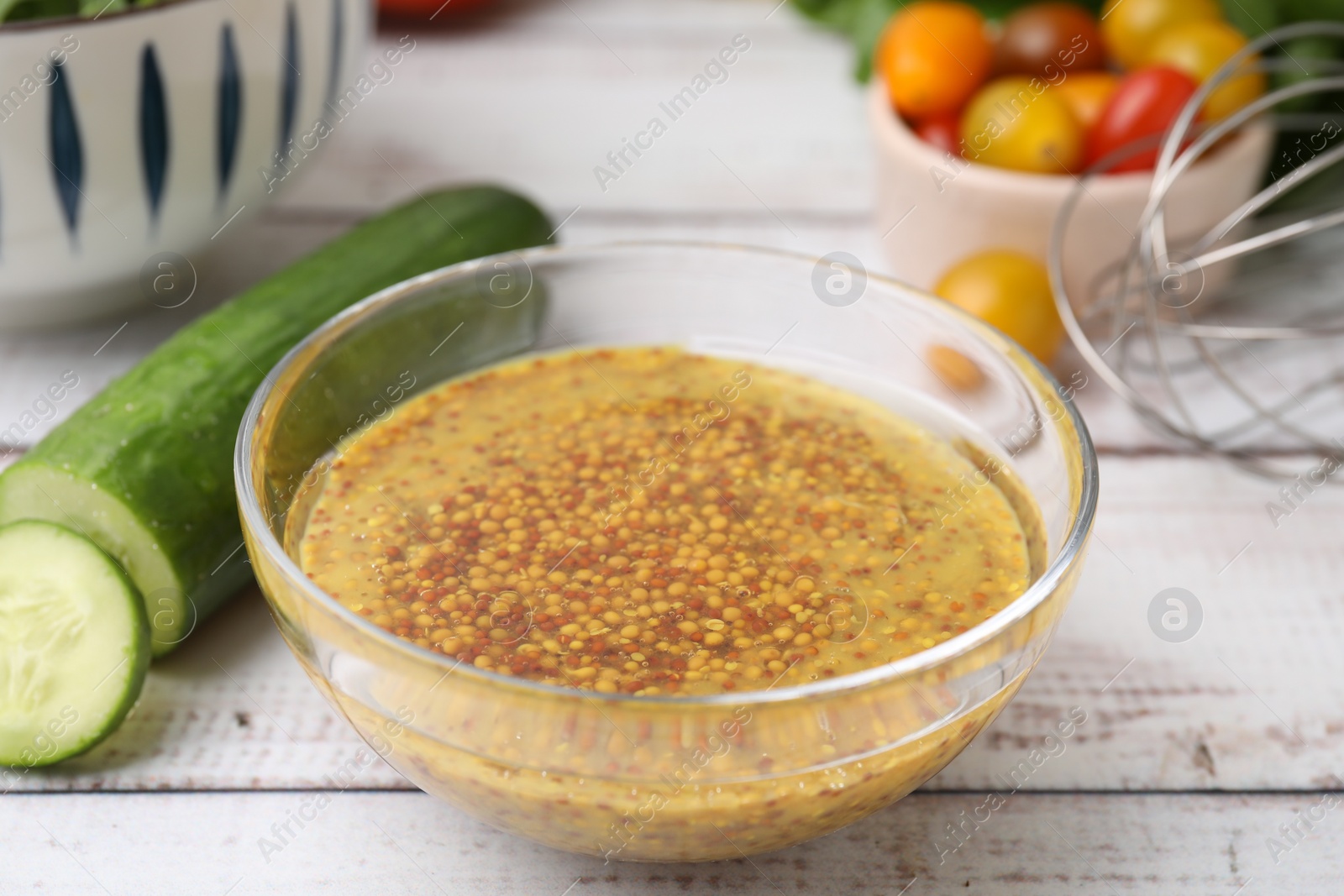 Photo of Tasty vinegar based sauce (Vinaigrette) in bowl and cucumber on wooden rustic table, closeup