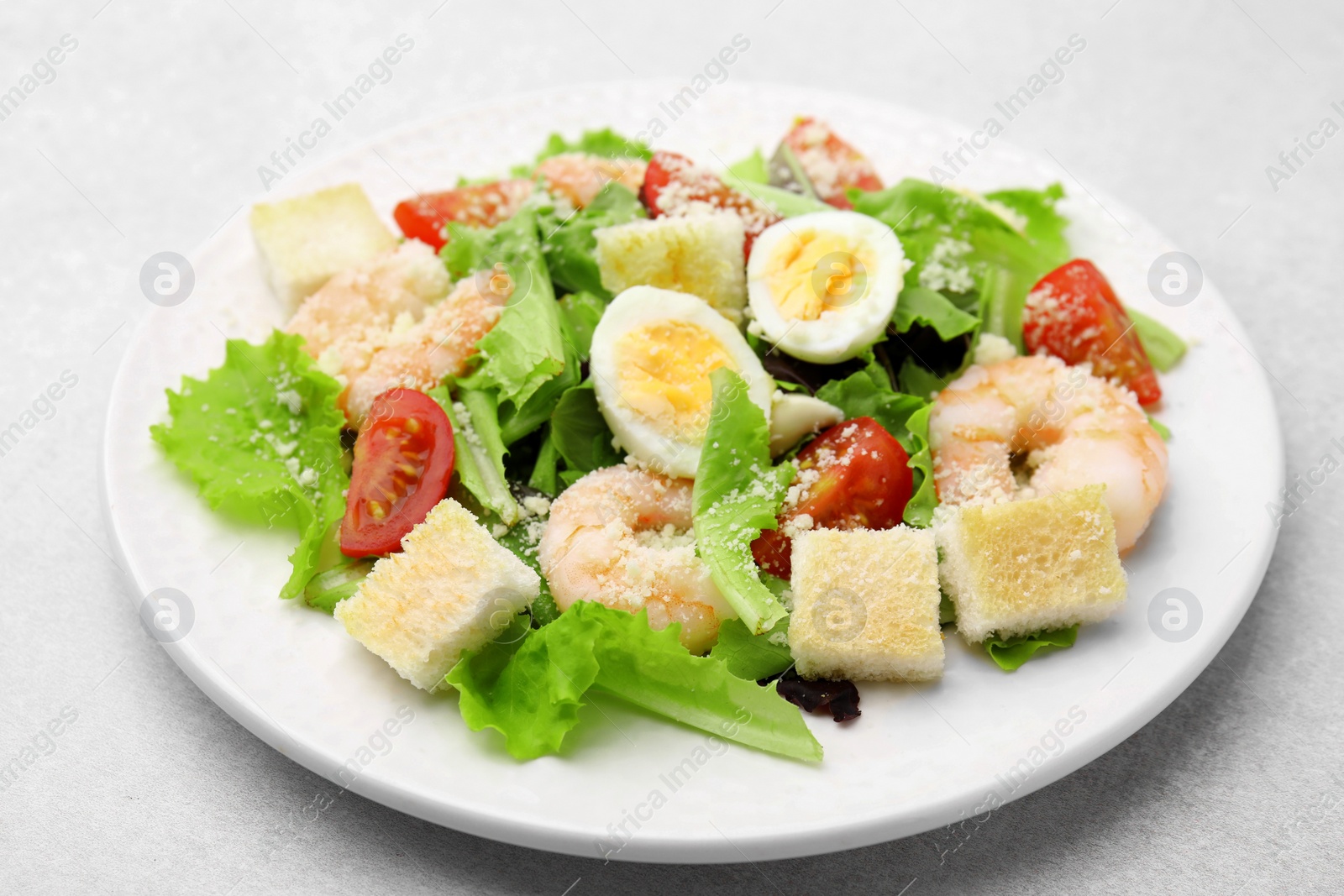 Photo of Delicious Caesar salad with shrimps on light table, closeup