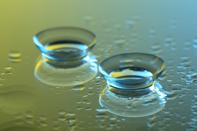 Pair of contact lenses on wet mirror surface, closeup