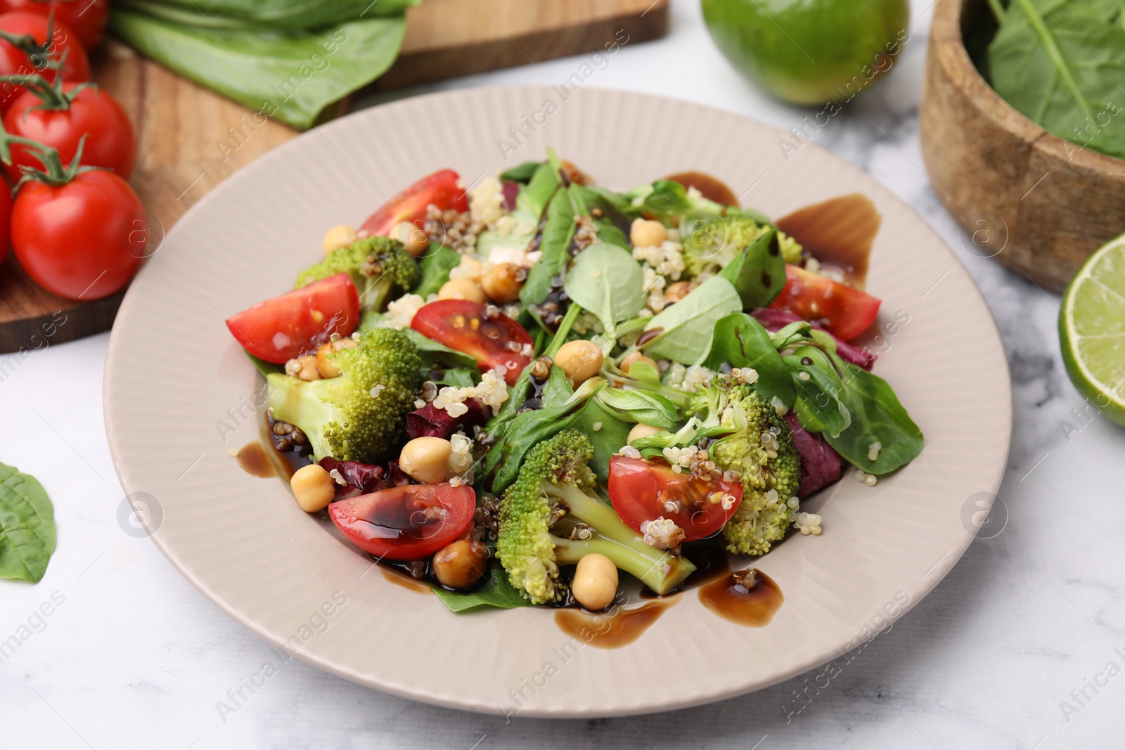 Photo of Tasty salad with balsamic vinegar on white marble table, closeup