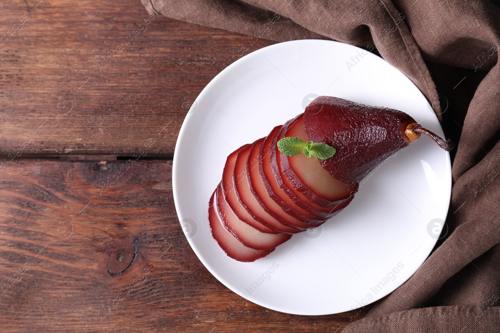 Photo of Tasty red wine poached pear on wooden table, top view. Space for text