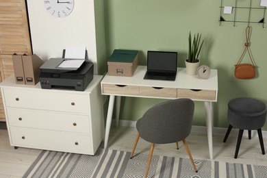 Photo of Stylish workplace with laptop and modern printer indoors