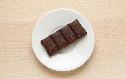 Photo of White plate with delicious and healthy hematogen bar  on wooden table, top view
