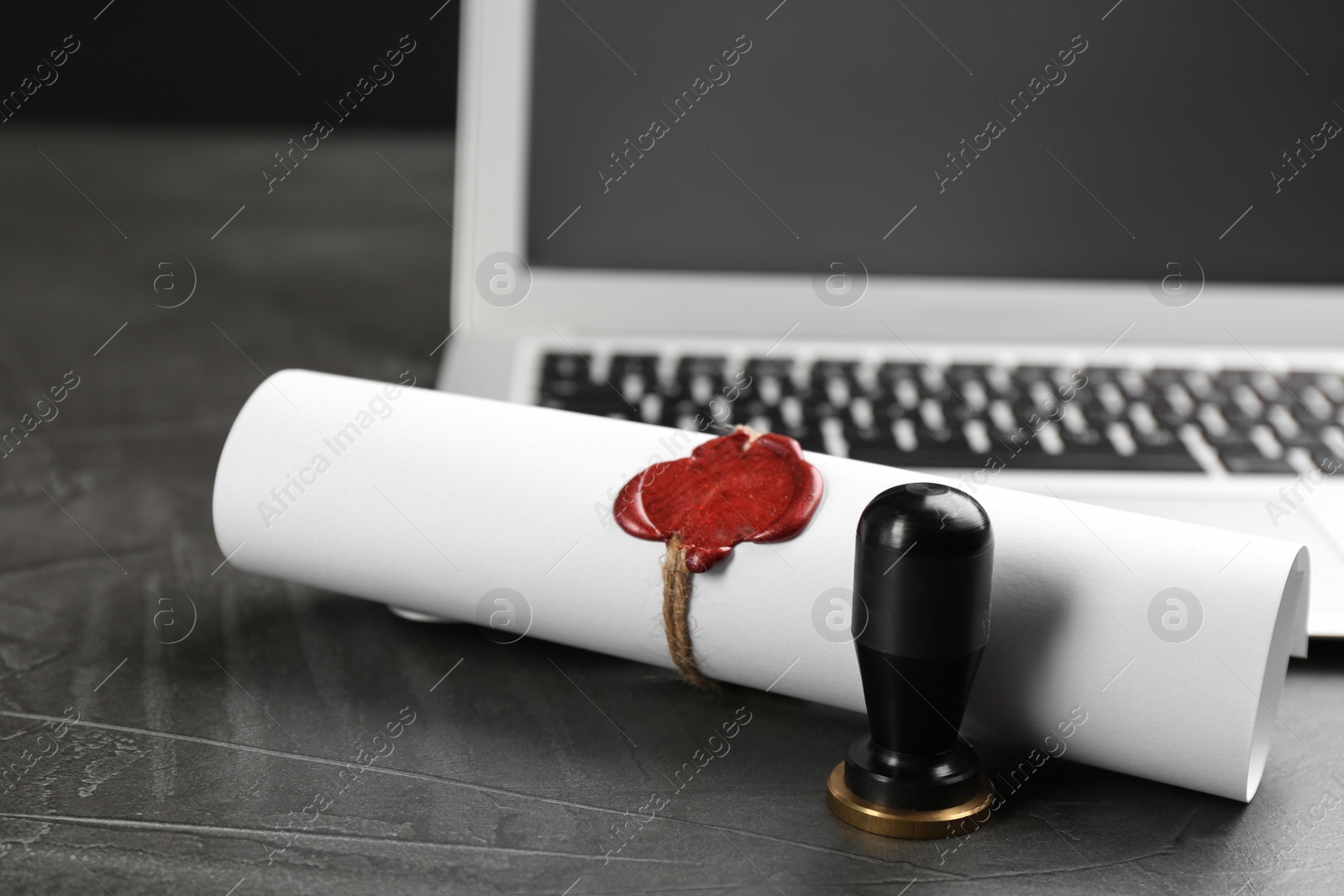 Photo of Notary's public pen and sealed document near laptop on grey stone table, closeup