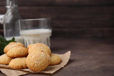 Photo of Tasty sweet sugar cookies and milk on brown table, closeup. Space for text