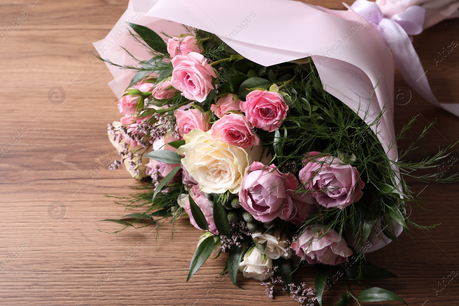 Photo of Beautiful bouquet with roses on wooden table
