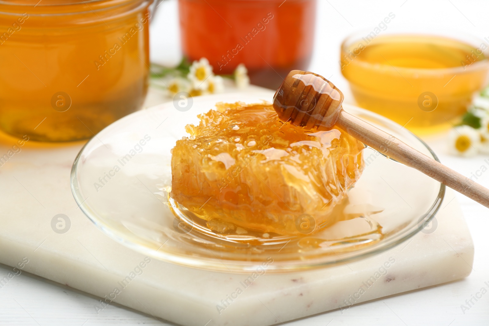 Photo of Tasty honey comb on light marble board, closeup