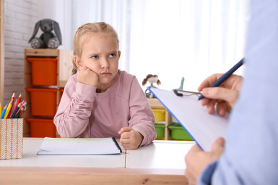 Little girl on appointment with child psychotherapist indoors