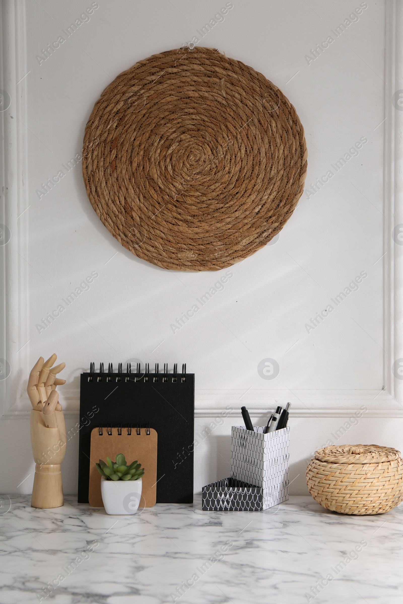 Photo of Stylish office workplace. Decor elements, houseplant and stationery on marble table near white wall