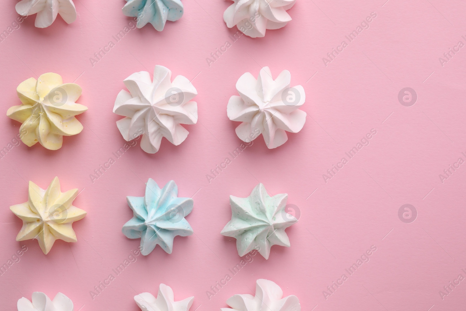 Photo of Many tasty meringue cookies on pink background, flat lay. Space for text