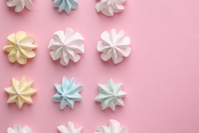 Many tasty meringue cookies on pink background, flat lay. Space for text