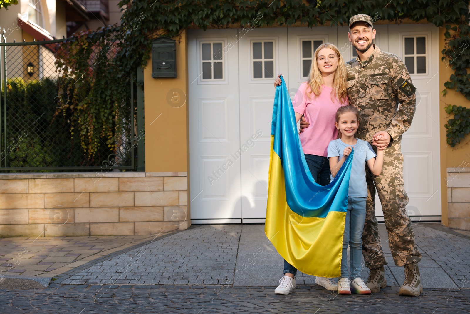 Photo of Soldier in military uniform reunited with his family and Ukrainian flag on city street, space for text