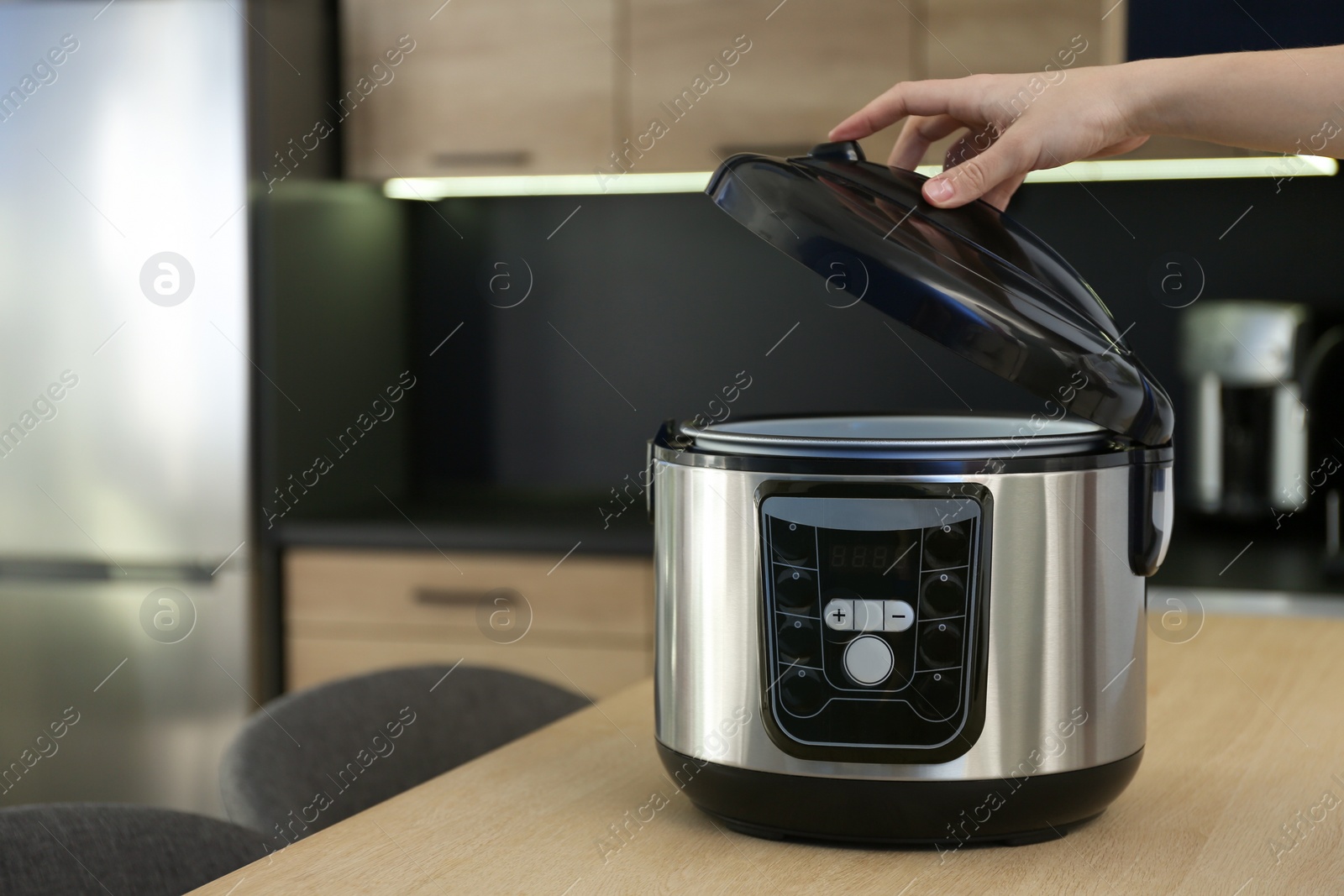 Photo of Young woman using modern multi cooker in kitchen, space for text