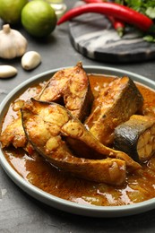 Photo of Tasty fish curry and ingredients on grey textured table, closeup. Indian cuisine