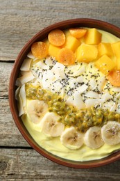 Photo of Tasty smoothie bowl with fresh fruits on wooden table, top view