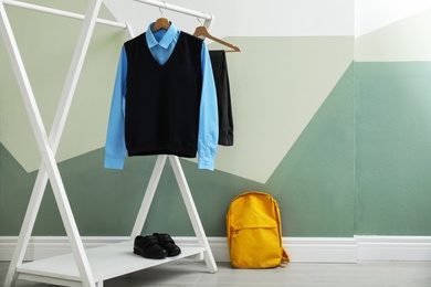 Photo of School uniform for boy on rack near color wall