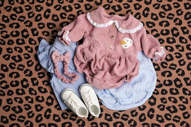 Photo of Baby girl clothes, shoes and accessories on leopard fabric, flat lay