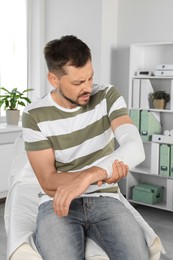 Photo of Man with arm wrapped in medical bandage at hospital