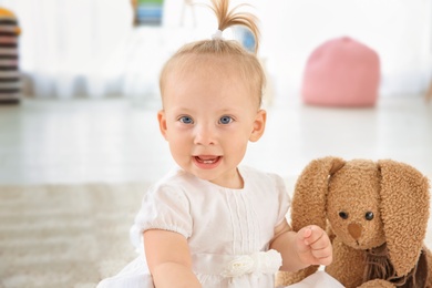 Photo of Adorable baby girl with cute toy at home