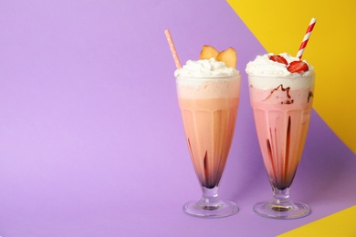 Photo of Glasses of tasty milk shakes and space for text on color background