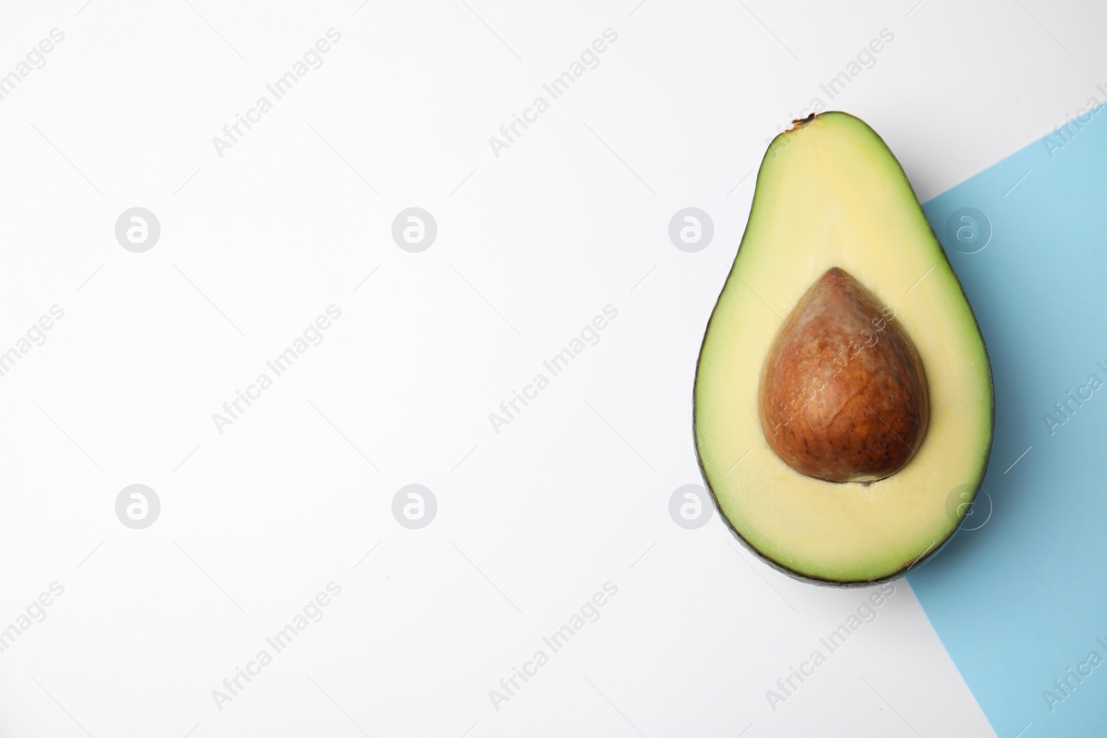 Photo of Cut fresh ripe avocado on color background, top view with space for text