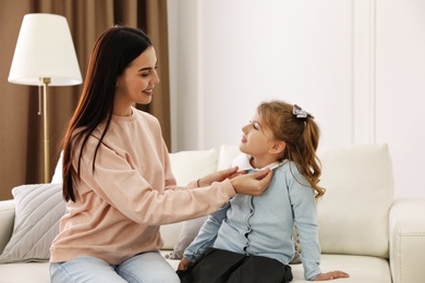 Photo of Young mother helping her little child get ready for school at home