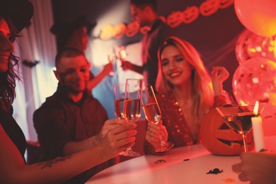 Photo of Group of friends toasting with champagne at Halloween party indoors