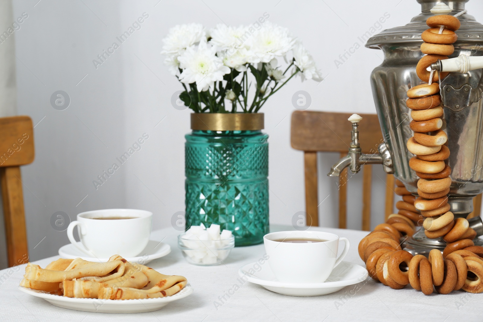 Photo of Vintage samovar, cup of hot drink and snacks served on table indoors. Traditional Russian tea ceremony