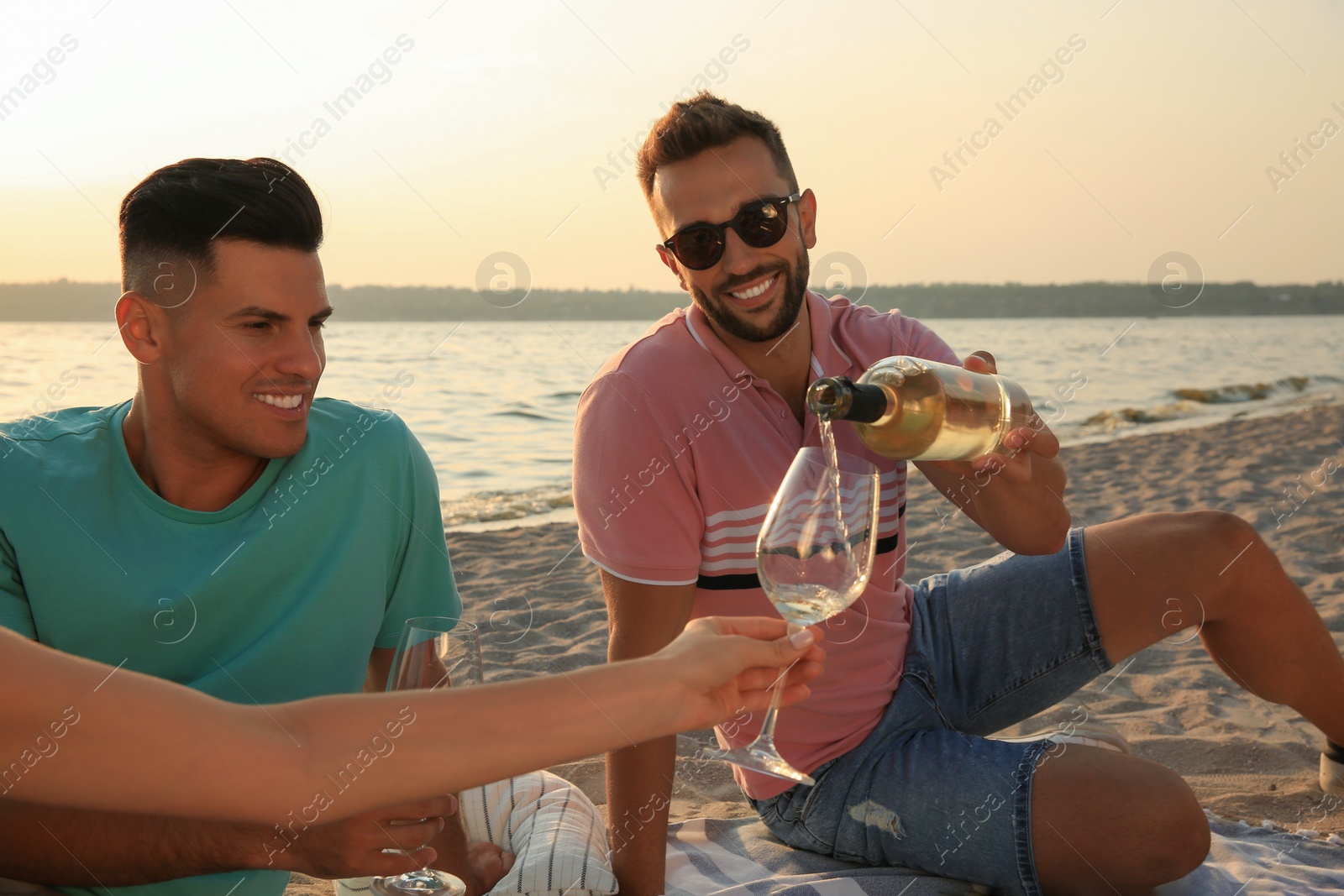 Photo of Group of friends having picnic outdoors at sunset