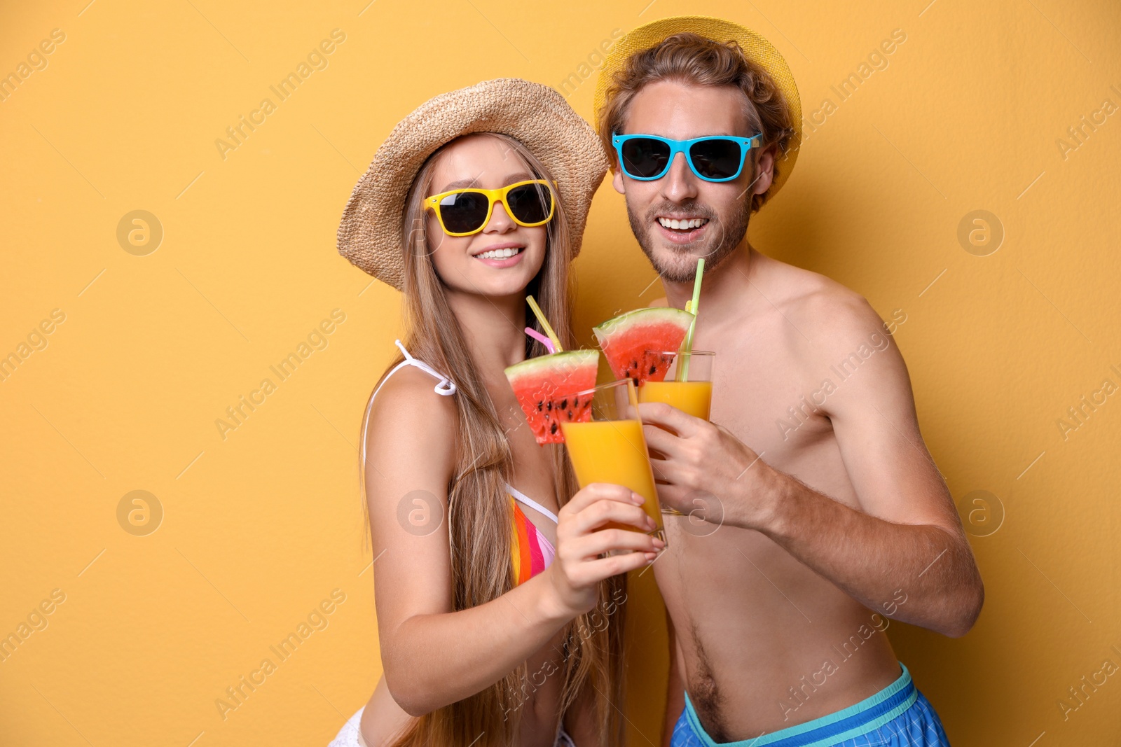 Photo of Young couple in beachwear with cocktails on color background