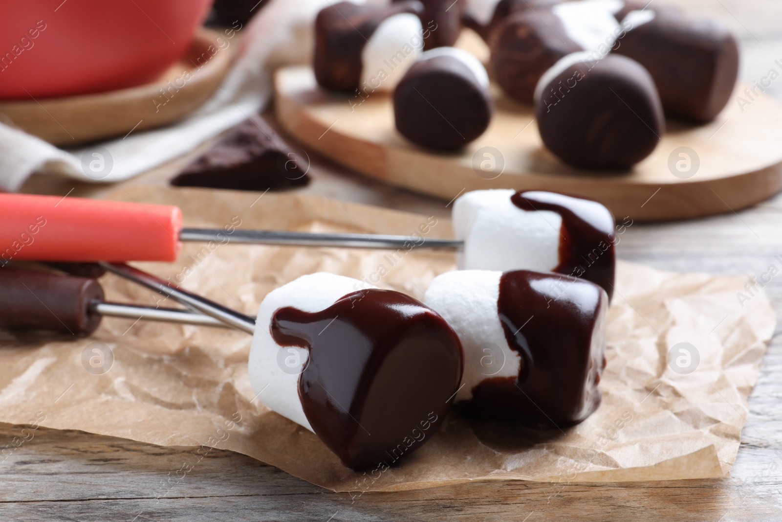 Photo of Delicious marshmallows covered with chocolate on wooden table, closeup