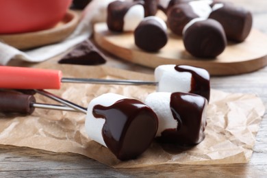 Photo of Delicious marshmallows covered with chocolate on wooden table, closeup