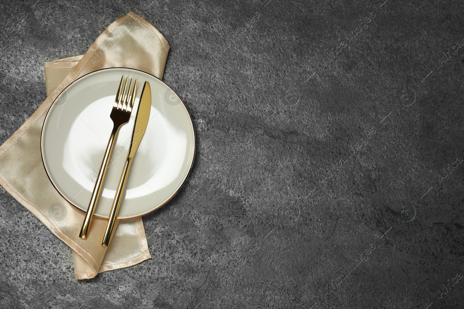 Photo of Stylish setting with elegant cutlery on grey table, top view. Space for text