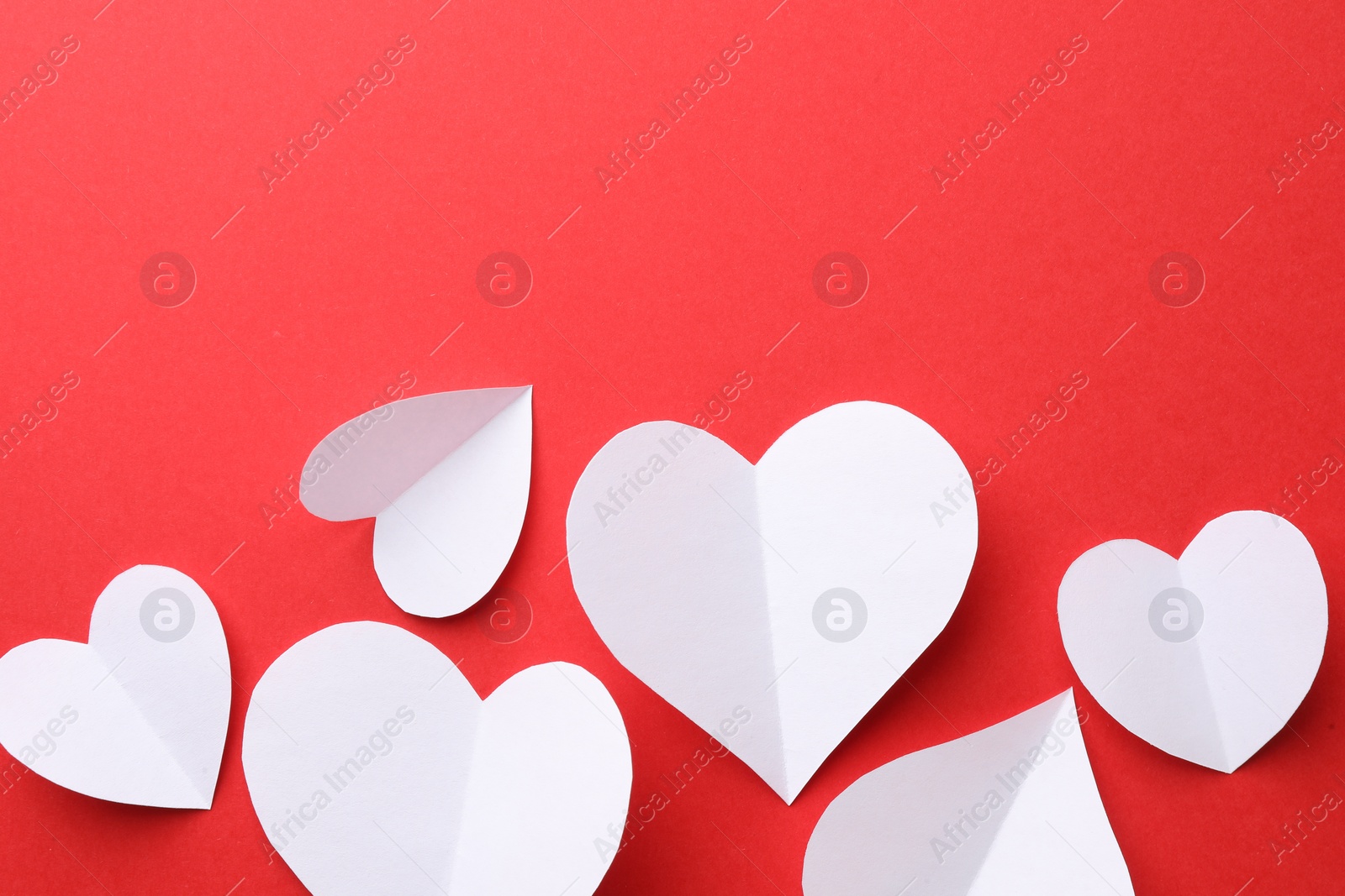 Photo of White paper hearts on red background, flat lay. Space for text