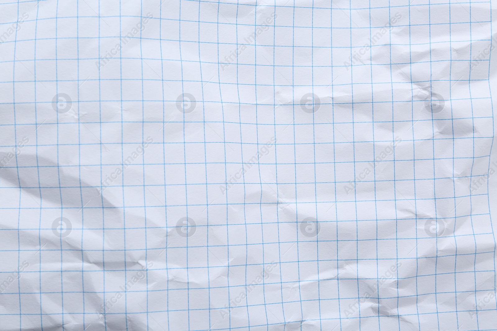 Photo of Crumpled checkered notebook sheet as background, top view