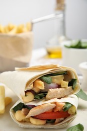 Delicious shawarmas with chicken and fresh vegetables on white table, closeup
