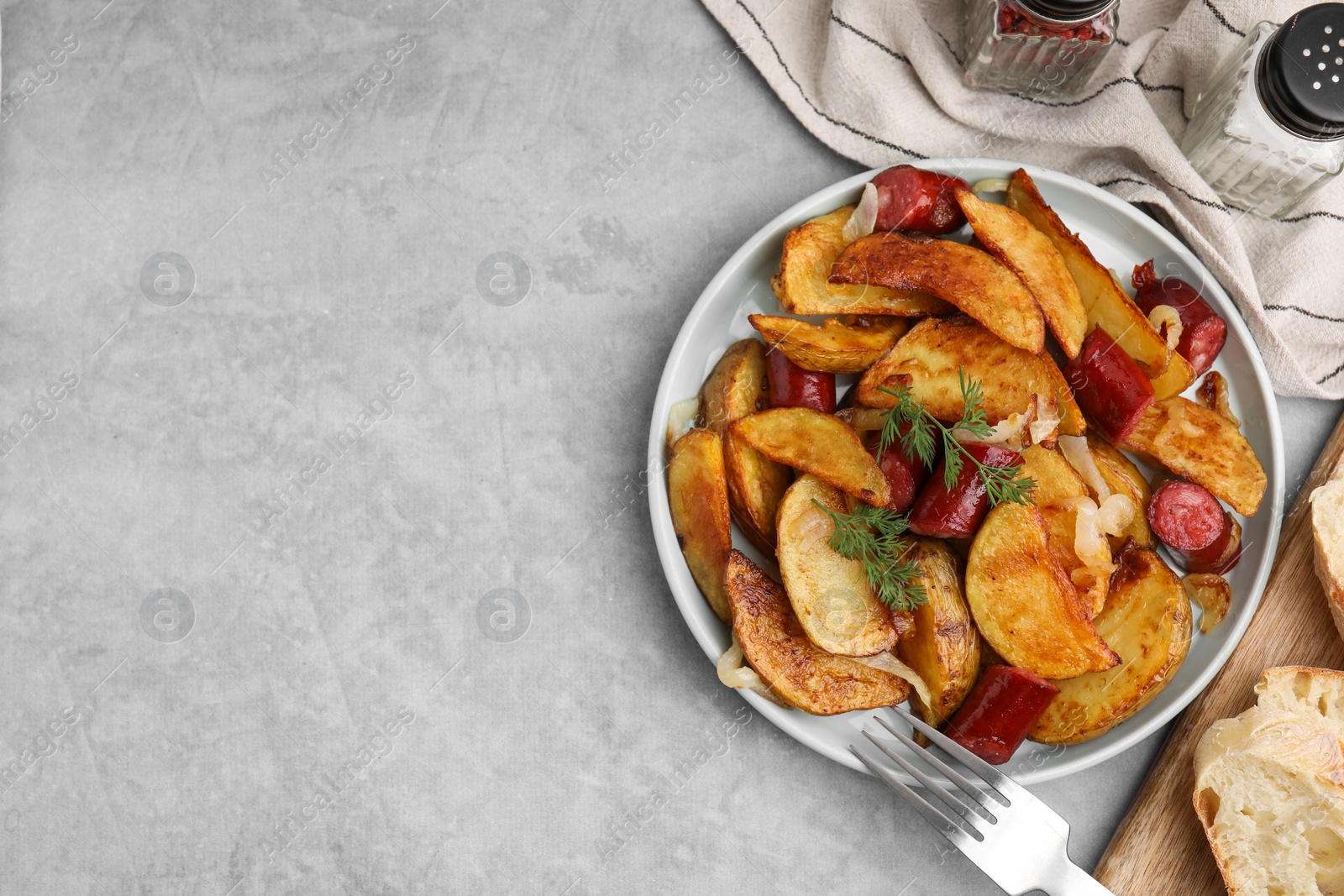 Photo of Delicious baked potato with thin dry smoked sausages served on gray table, flat lay. Space for text