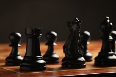 Photo of Chessboard with game pieces on dark background, closeup