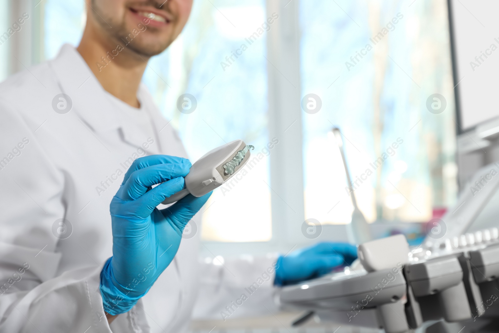 Photo of Sonographer holding ultrasound machine probe with gel in clinic, closeup. Space for text
