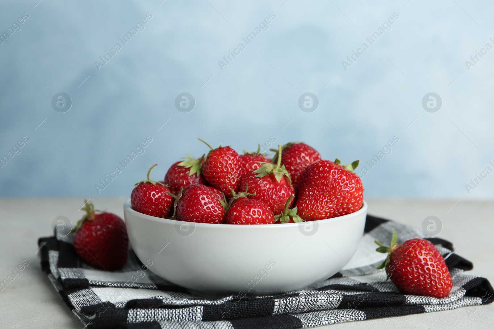 Photo of Delicious ripe strawberries in bowl on table