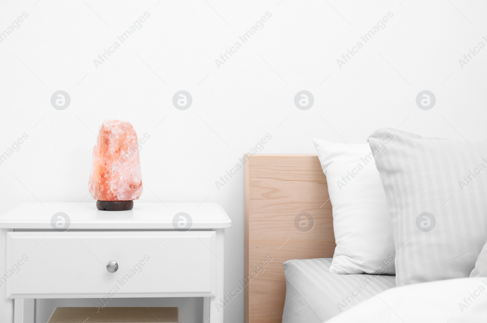 Photo of Himalayan salt lamp on white nightstand in bedroom