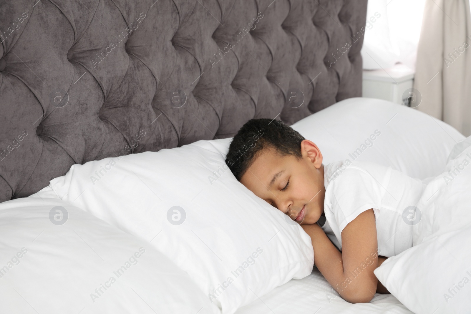 Photo of Cute little African-American boy sleeping in bed. Space for text