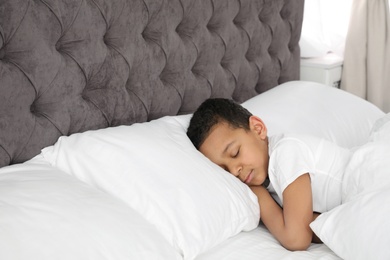 Photo of Cute little African-American boy sleeping in bed. Space for text