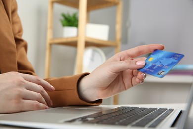 Photo of Online payment. Woman with credit card using laptop indoors, closeup