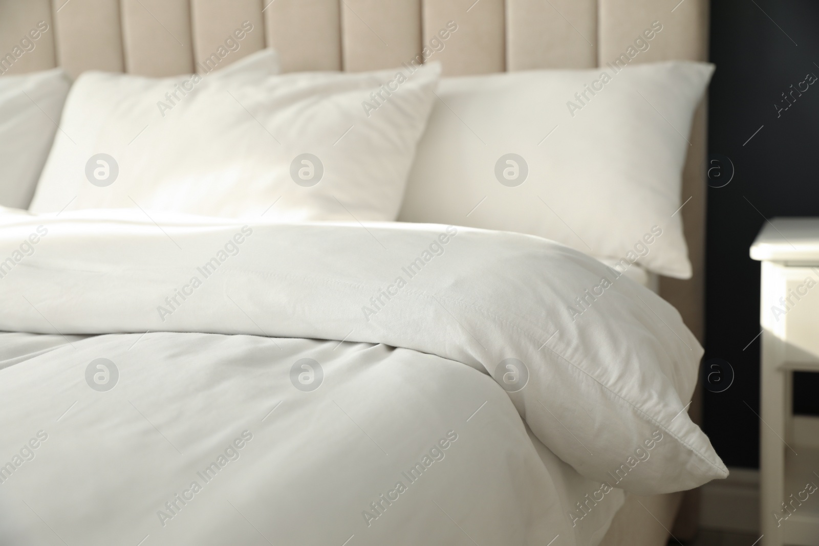 Photo of Comfortable bed with soft blanket and pillows indoors, closeup