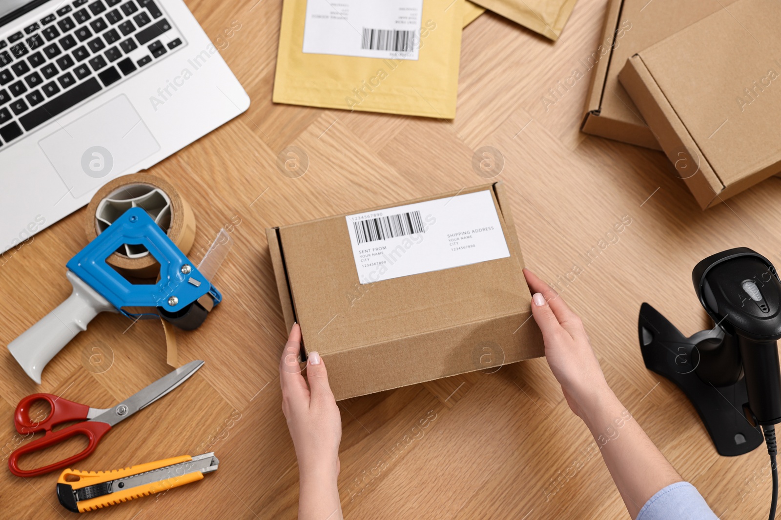 Photo of Post office worker packing parcel at wooden table, top view